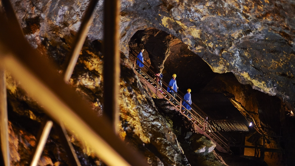 Menschen mit Helmen und blauer Kleidung in einer beleuchteten Mine